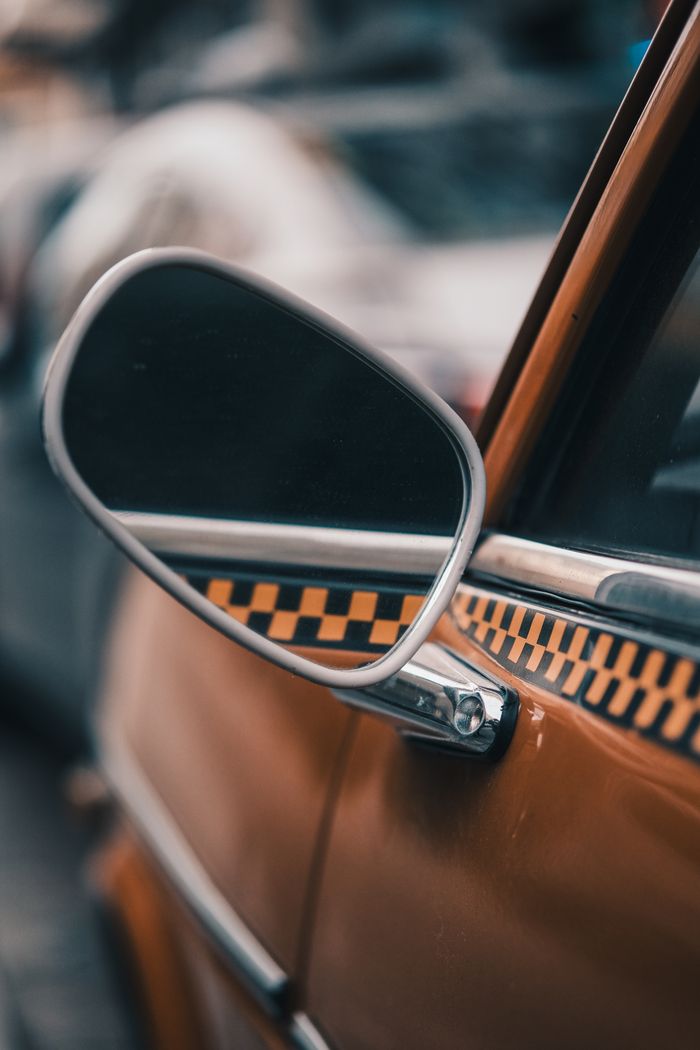Detailed view of side mirror on a classic vintage taxi with distinctive checkered pattern.